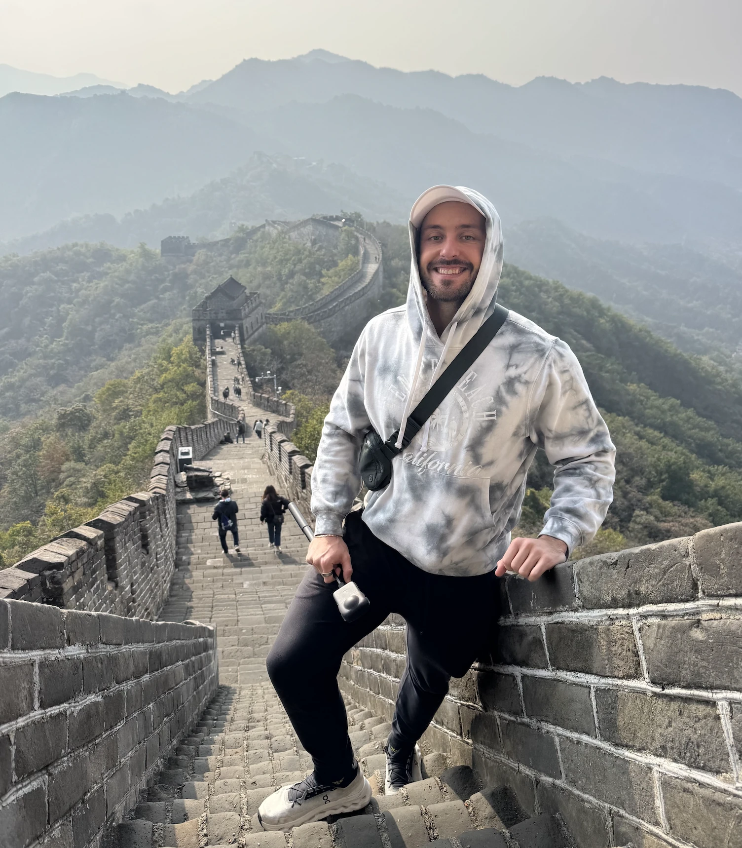 Jake on the Great Wall of China, with mountains behind him